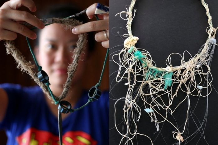 A woman holds a necklace made of rope, sinkers and plastic piping, and a necklace made of string and fishing line on a table. |700x467