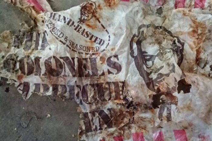 A torn, branded plastic bag is spread out on a concrete floor.|700x467