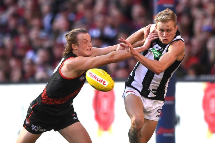 An AFL player pushes another AFL player with both hands as they contest for the mid-air ball.|700x467