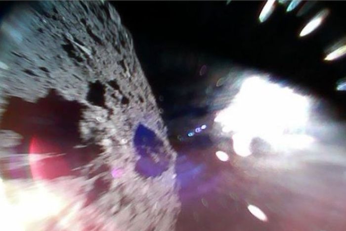 Picture shows the surface of the asteroid on the left and a white sun glare on the right|700x467